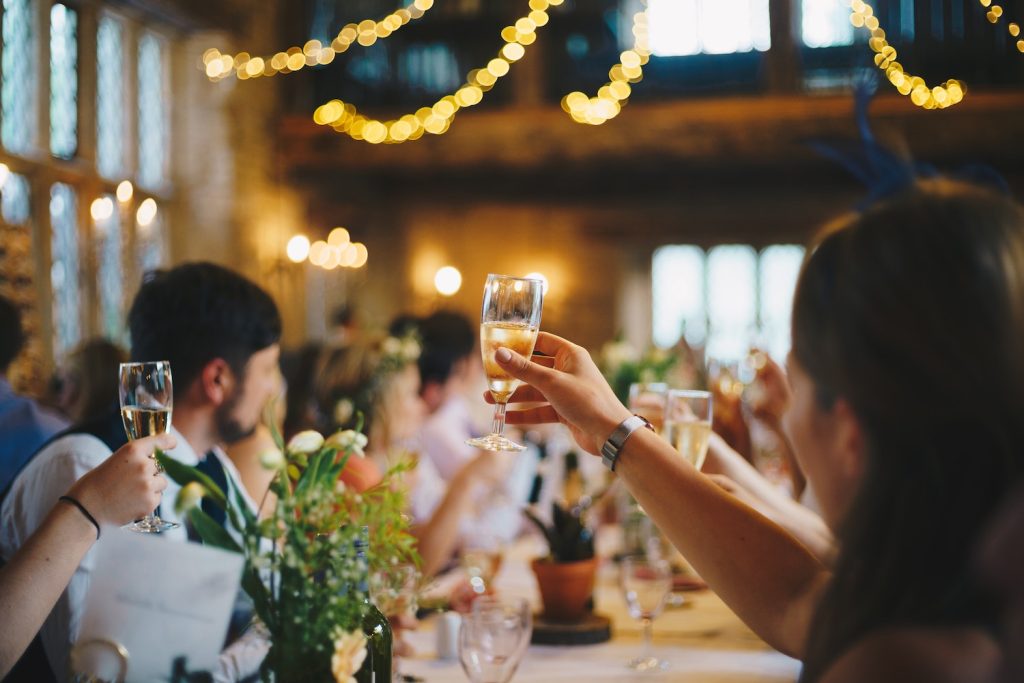 After-Wedding-Party - Gäste feiern Brautpaar mit erhobenen Gläsern
