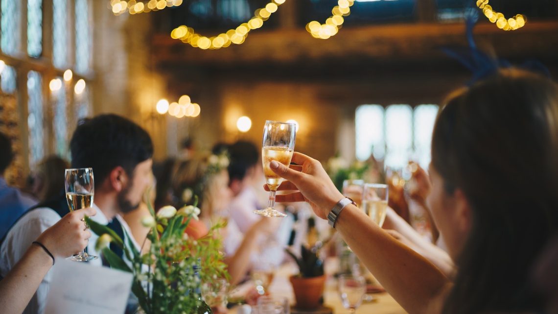 After-Wedding-Party - Gäste feiern Brautpaar mit erhobenen Gläsern