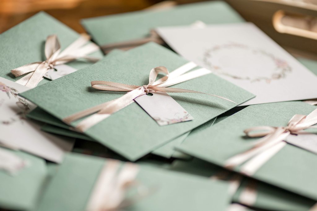Grüne Umschläge mit zartrosa Schleifen als Hochzeitseinladungen