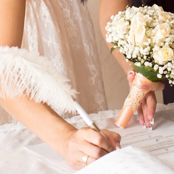 Braut unterzeichnet Ehedokumente nach Trauung im Standesamt