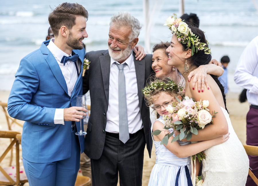 Brautpaar feiert Vermählung mit Brauteltern am Strand