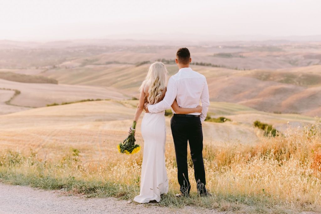 Brautpaar umarmt sich und schaut in die weite Hügellandschaft